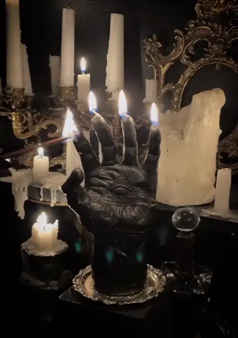 Witchcraft hand statue with candles and spellcasting tools
