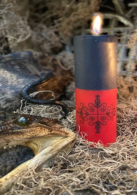 Candle with mystical signs surrounded by ritual tools used for voodoo and witchcraft removal